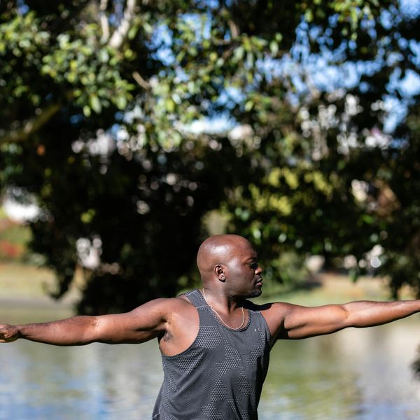Man feeling energized and stretching outdoors with the sun in the background.